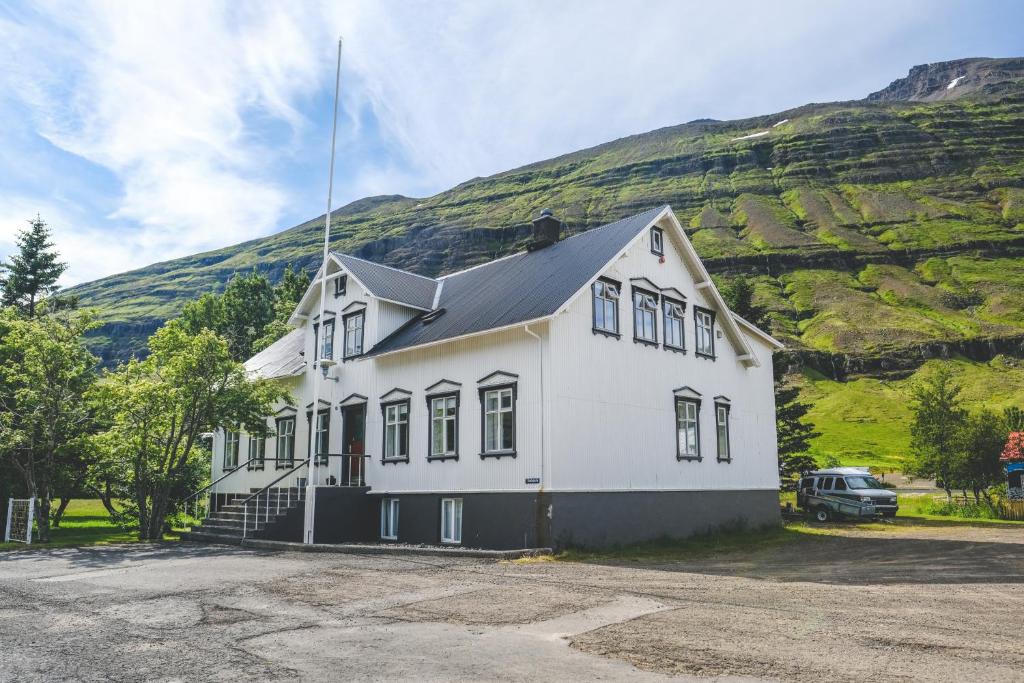 
a white house sitting on top of a hill at Hotel Aldan - The Bank in Seyðisfjörður
