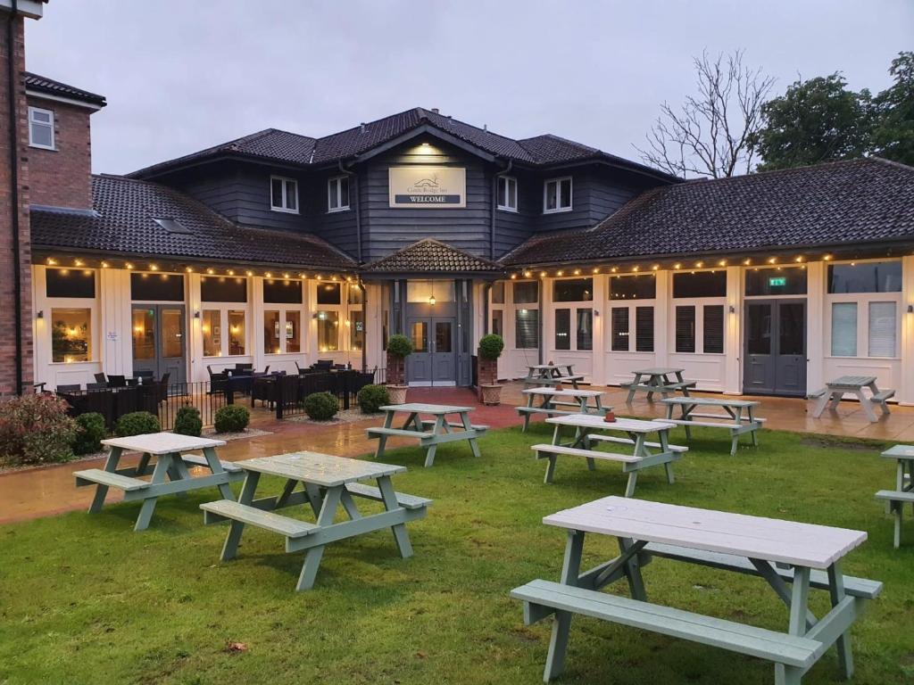 un grupo de mesas de picnic frente a un edificio en Cuttle Bridge Inn Hotel - NEC / Birmingham Airport, en Minworth