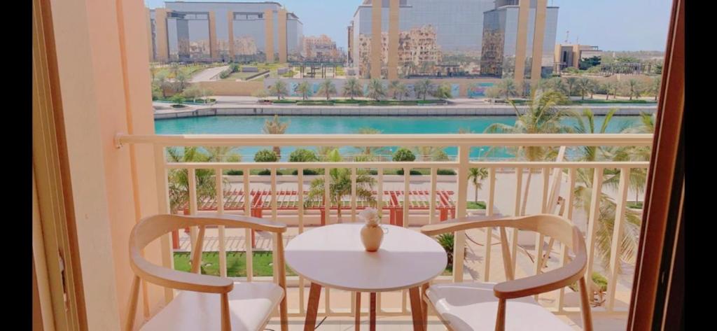 a table and chairs on a balcony with a view of a pool at Bay la sun , Luxury apartment with nice view in King Abdullah Economic City