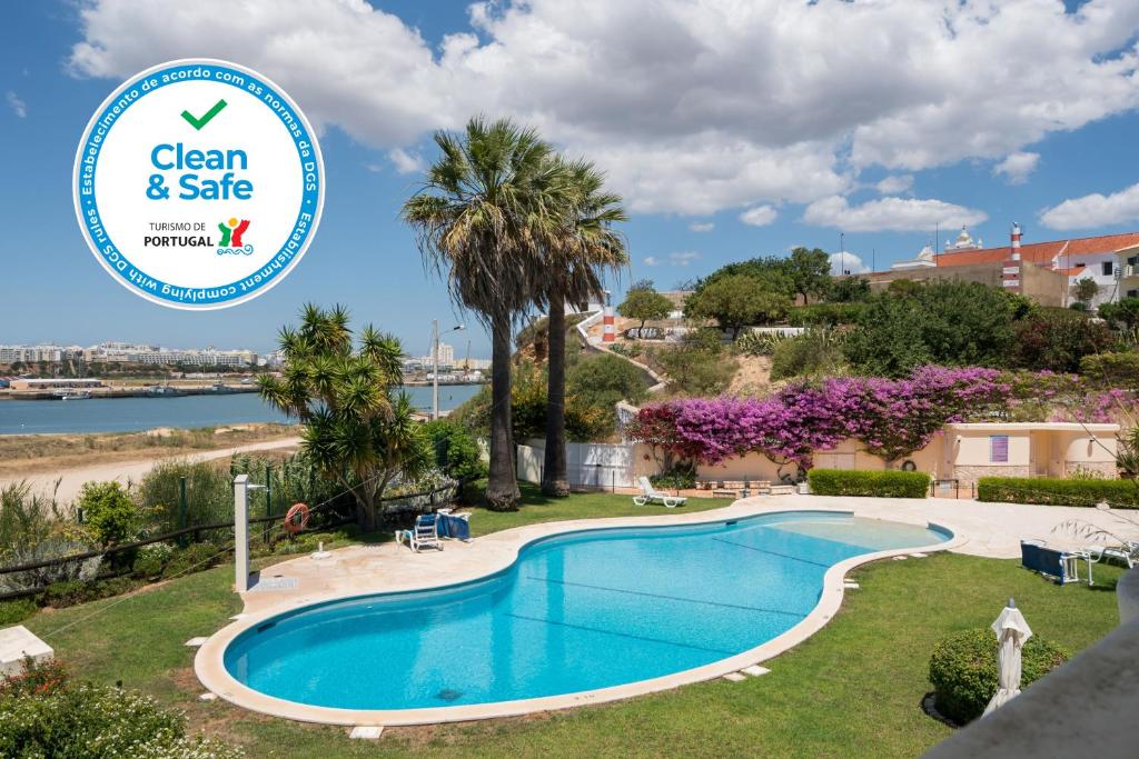 a swimming pool with a sign that reads clean safe at One Bedroom Sea View Apartment Clube Rio Ferragudo in Ferragudo