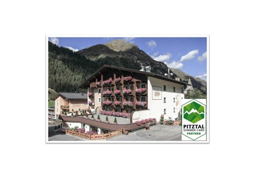 ein großes Gebäude mit einem Berg im Hintergrund in der Unterkunft Hotel Bergland Superior in Sankt Leonhard im Pitztal