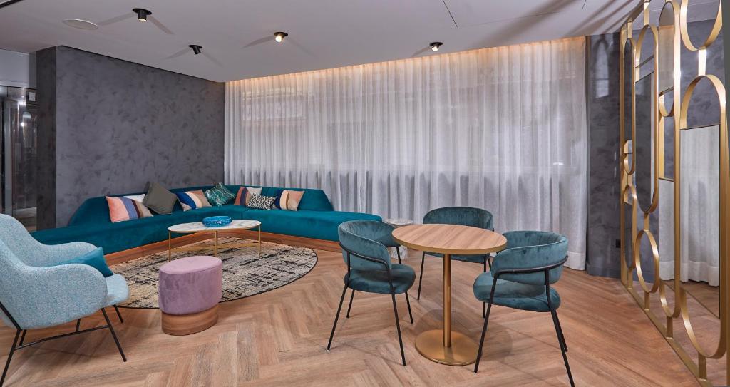 a living room with a blue couch and chairs at Occidental Alicante in Alicante