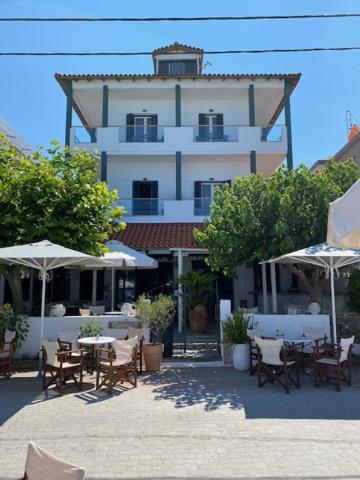a building with tables and umbrellas in front of it at Xenios Hotel in Pefkochori