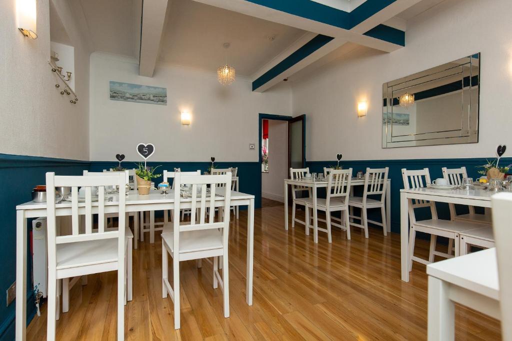 une salle à manger avec des tables et des chaises blanches dans l'établissement The Carlton, à Blackpool