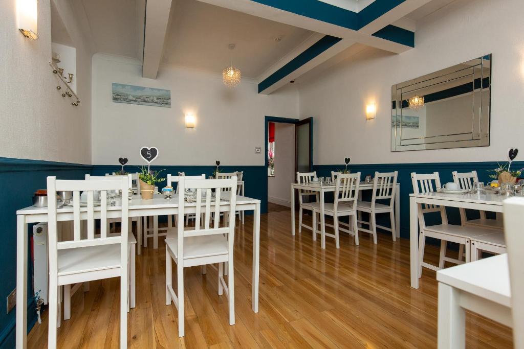 a dining room with white tables and white chairs at The Carlton in Blackpool