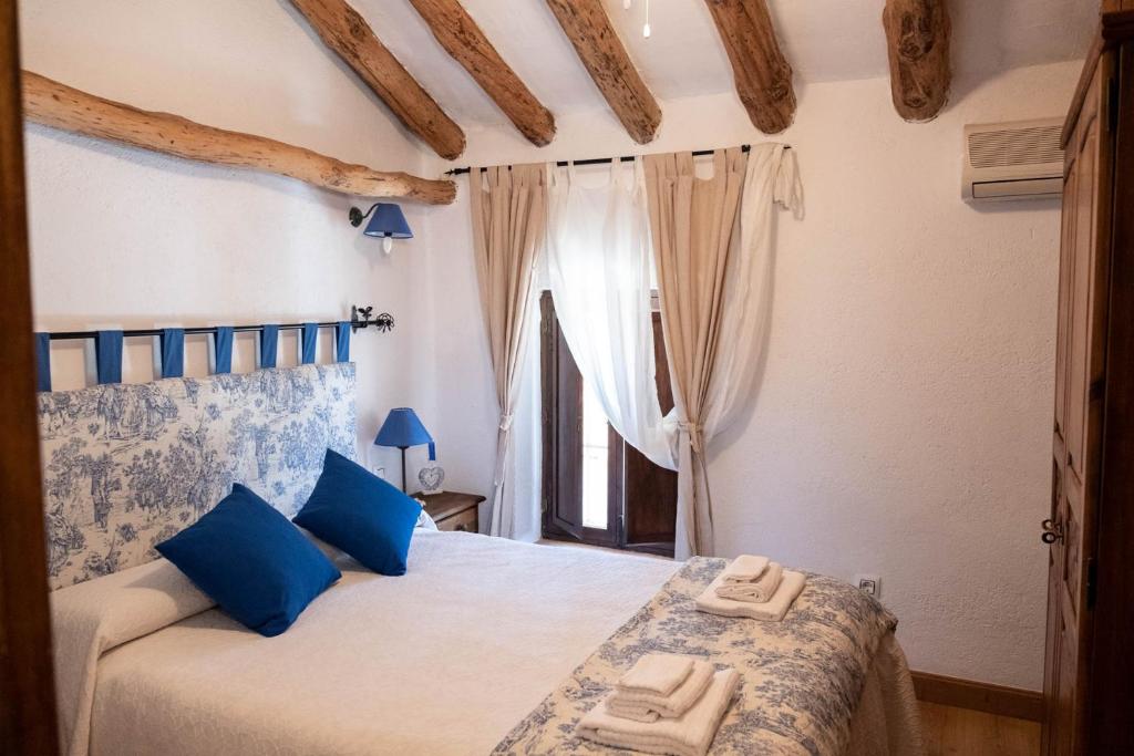Un dormitorio con una cama con almohadas azules y una ventana en Casa Rural los Enebros, en Los Navalucillos