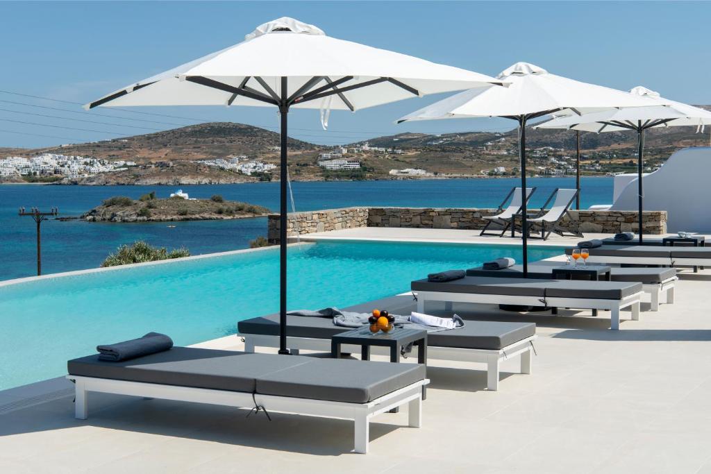 Kymo Luxury Suites Paros في Kolympithres: مسبح مع كراسي الصالة والمظلات