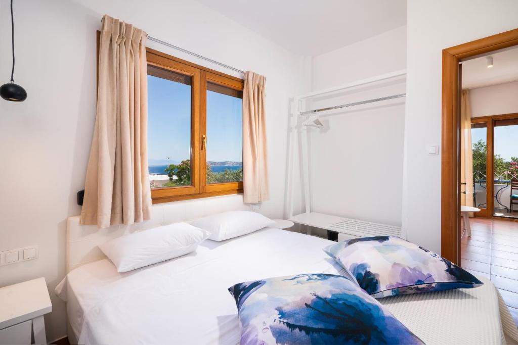 a bedroom with a bed and a large window at Villa Victoria by La Scala Beach in Limenas