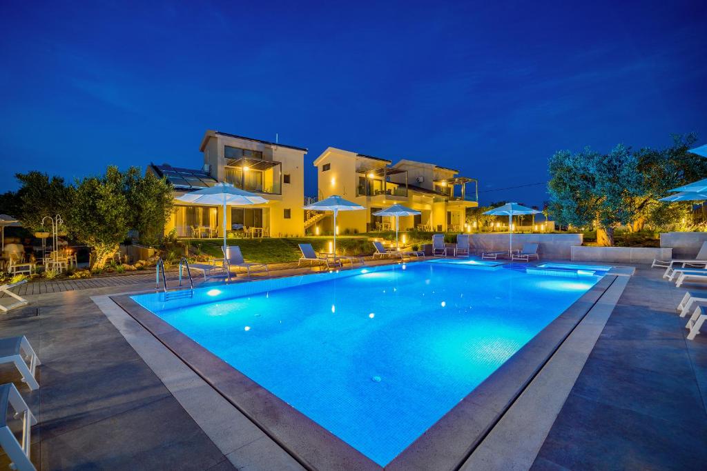 a swimming pool in front of a villa at night at Miroes Suites in Nikiti