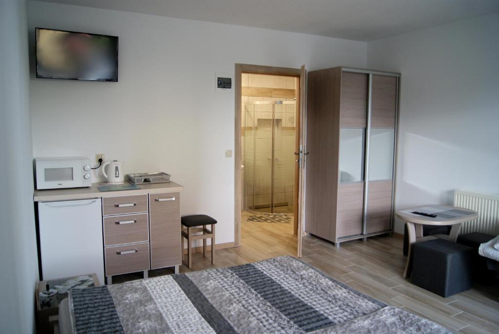 ein Schlafzimmer mit einem Bett und einem Schreibtisch sowie eine Küche in der Unterkunft Rega pokoje in Sarbinowo