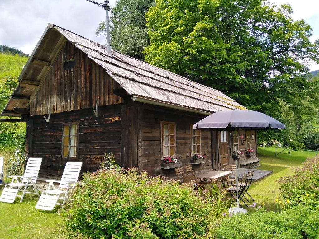 a small wooden cabin with chairs and an umbrella at Ferienhaus Lederer in Stockenboi