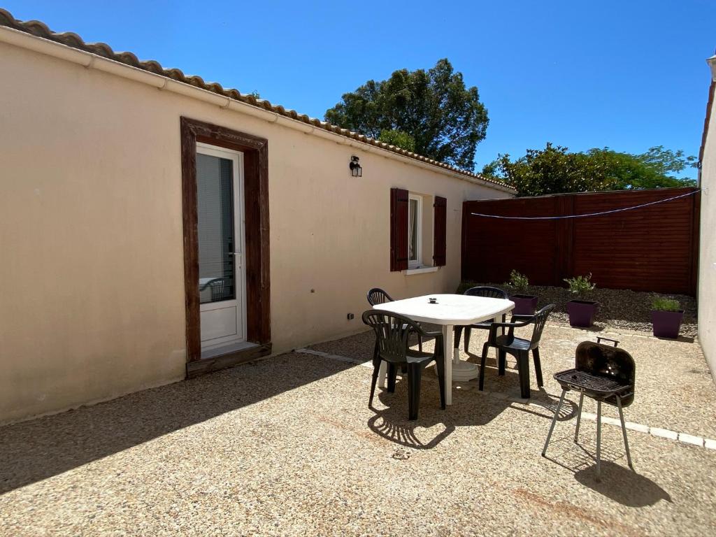 um pátio com uma mesa, cadeiras e uma cerca em MAISON *** AVEC COUR 3KM PLAGE ET LA ROCHELLE em Saint-Vivien