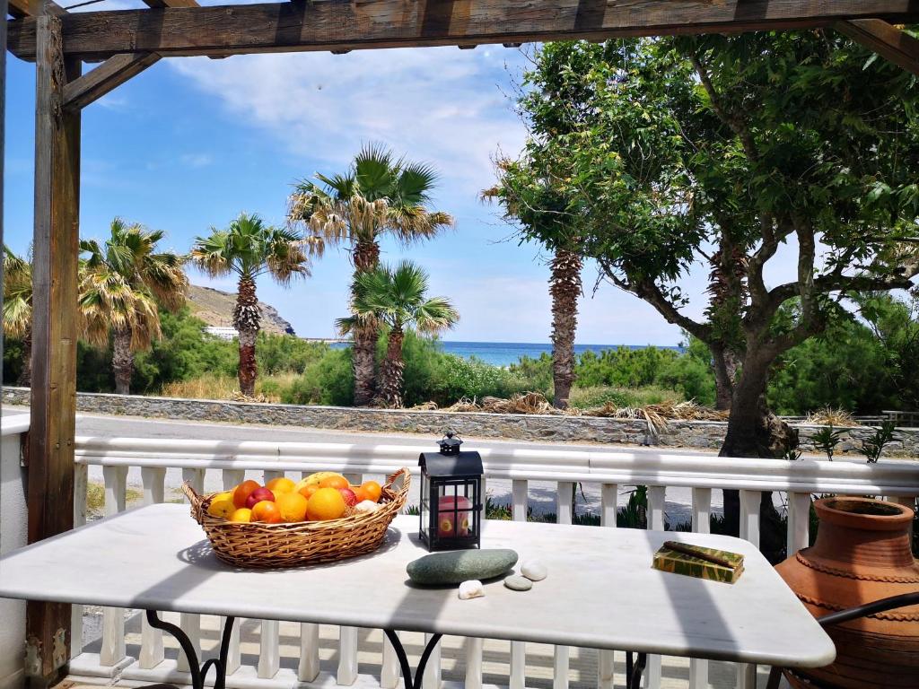 una cesta de fruta sentada en una mesa en un porche en By the sea en Andros