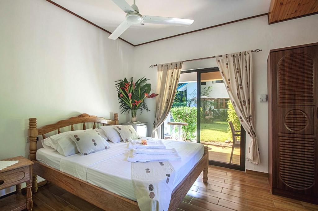 a bedroom with a bed with a ceiling fan at Tannette Villa in La Digue
