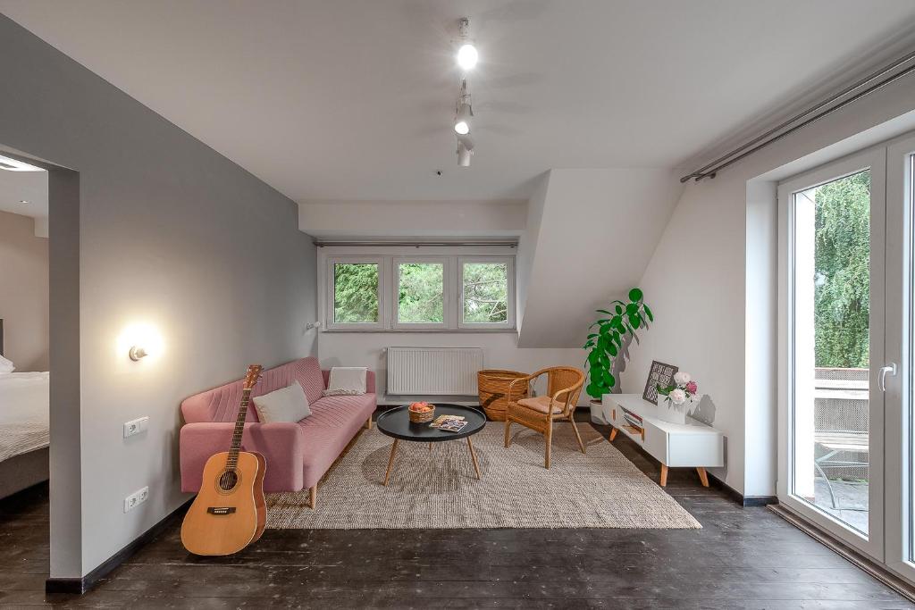 a living room with a pink couch and a guitar at Das Wiesenhaus: Wohnen direkt am Rhein in Cologne