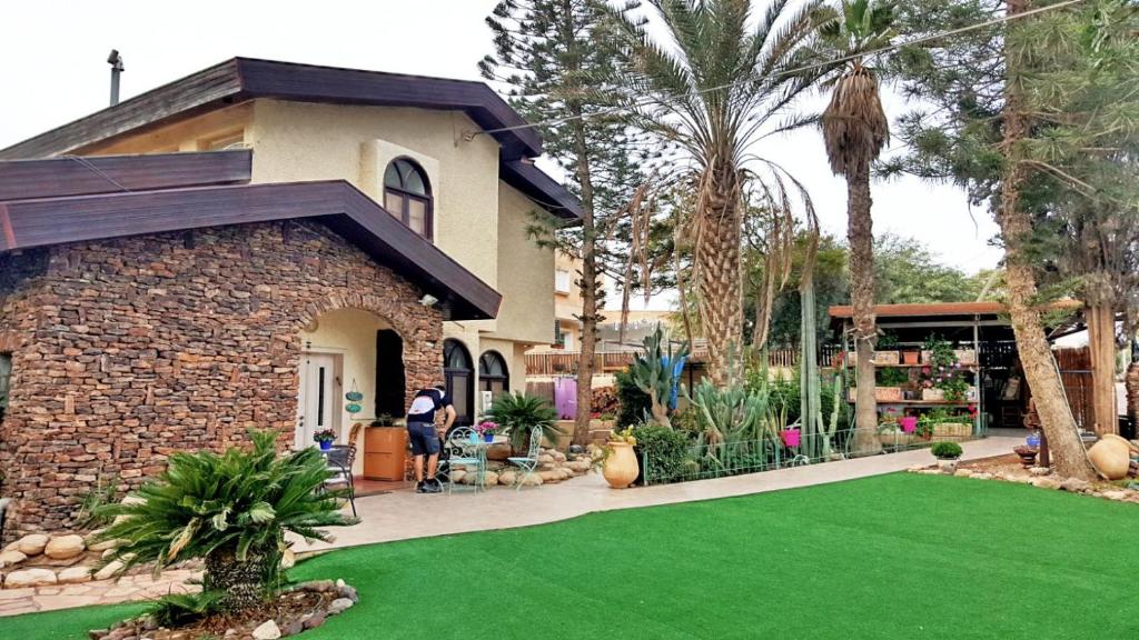 une maison avec une pelouse verte devant elle dans l'établissement Desert Bird Guest House, à Arad