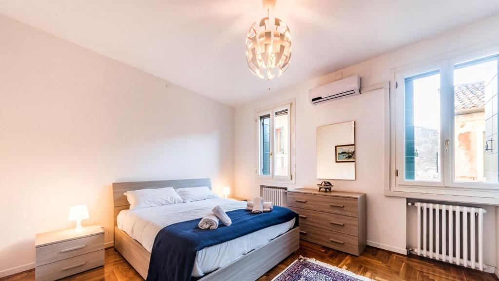 a bedroom with a bed and two windows and a chandelier at Residenza Canal in Venice