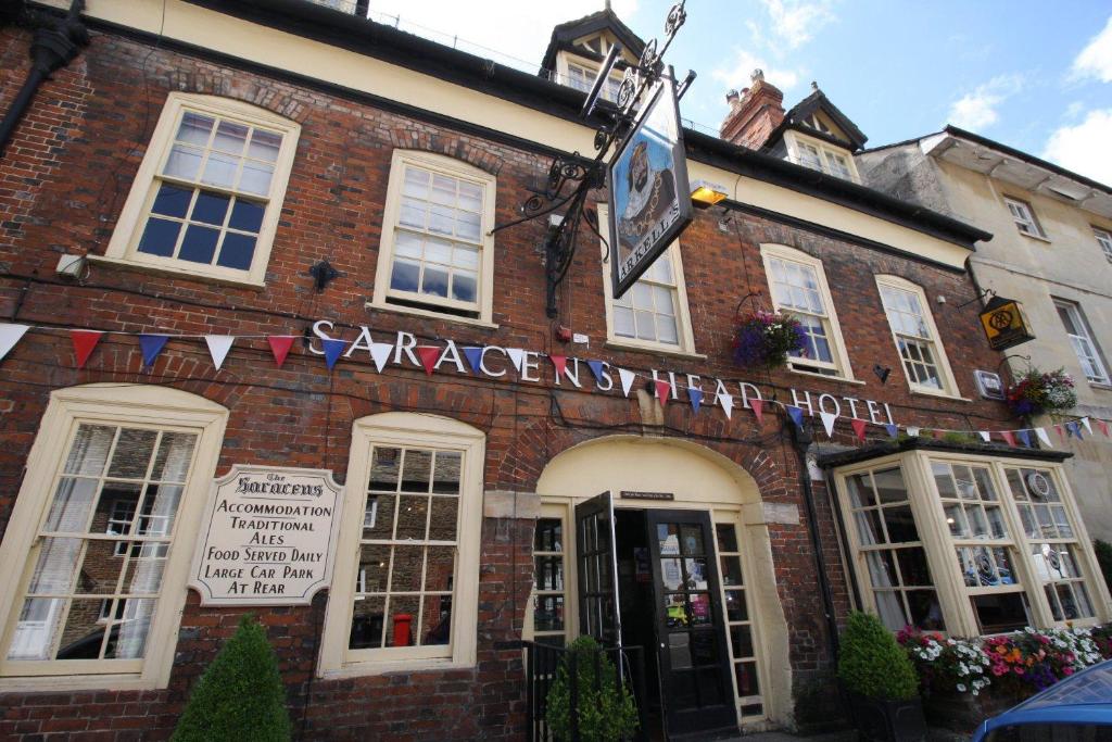 ein großes Backsteingebäude mit einem Schild darauf in der Unterkunft The Saracens Head Hotel in Highworth