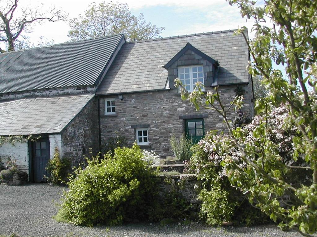 uma antiga casa de pedra com um telhado de gambrel em Alltybrain Farm Cottages and Farmhouse B&B em Brecon