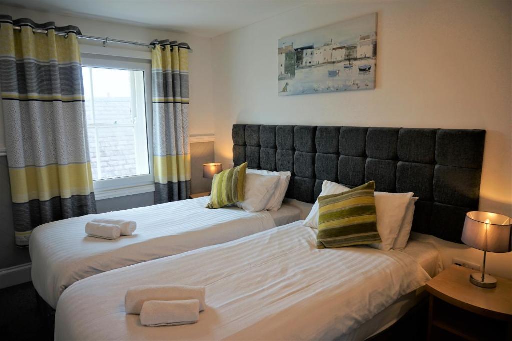 2 camas en una habitación con 2 lámparas y una ventana en The Angel Hotel, en Cardigan