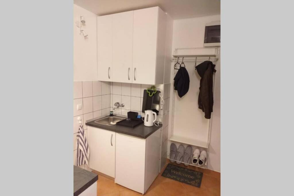 eine kleine Küche mit weißen Schränken und einem Kühlschrank in der Unterkunft Studio apartman Bruno in Zagreb