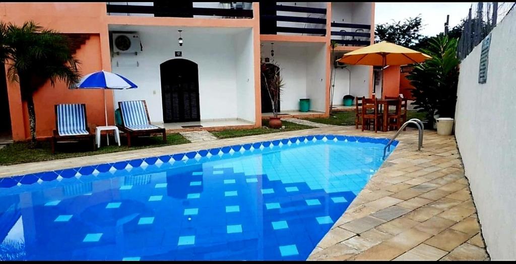 a blue swimming pool in front of a house at VILLA GARDEN - Suites in Maresias