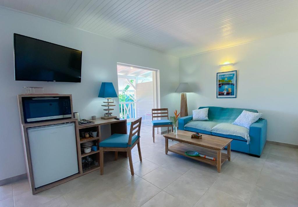 un soggiorno con un divano blu e una TV di LES HAUTS DU CAP a Le François