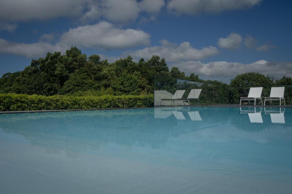 une piscine avec des chaises et des arbres en arrière-plan dans l'établissement Quinta dos 10, à Ponta Delgada