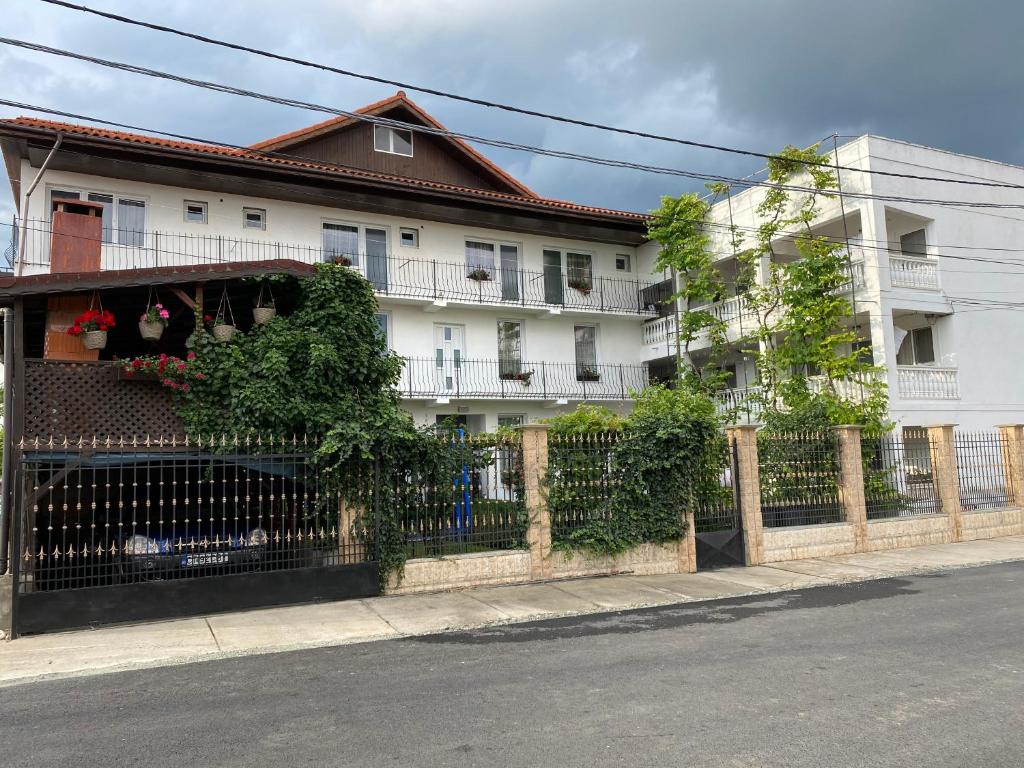 a white building with a fence next to a street at Casa Ciobi in 2 Mai