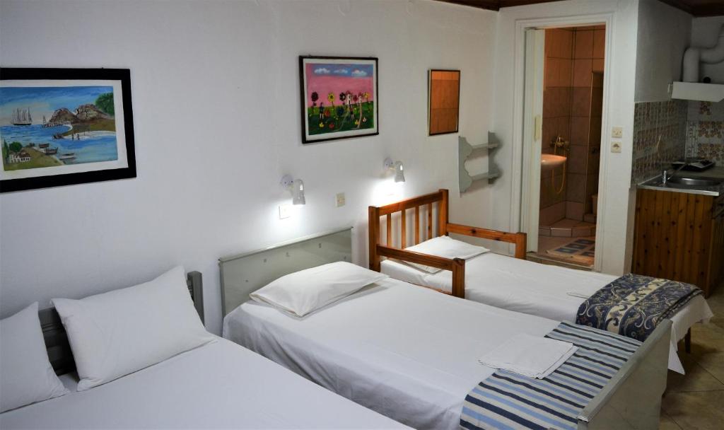 a bedroom with two beds and a bathroom at Evaggelou Rooms in Potos
