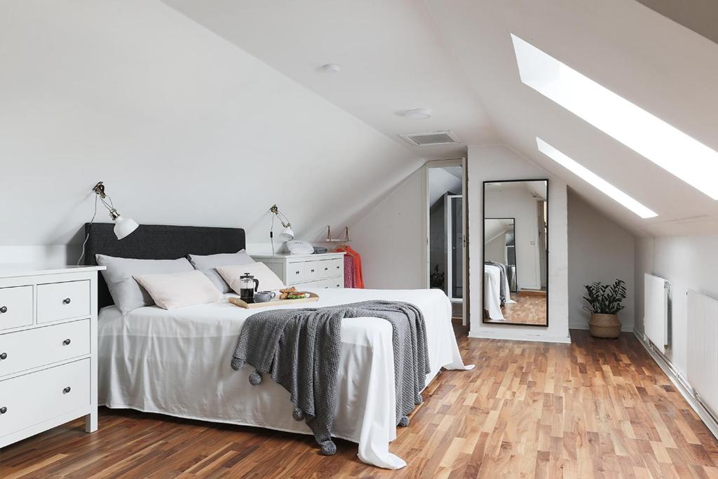 a white bedroom with a bed and a large mirror at Cozy Apartment in Uppsala