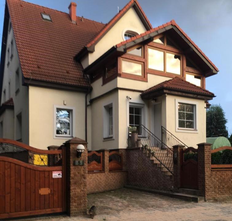 a white house with a gate and a fence at Apartamenty Słupskie in Słupsk