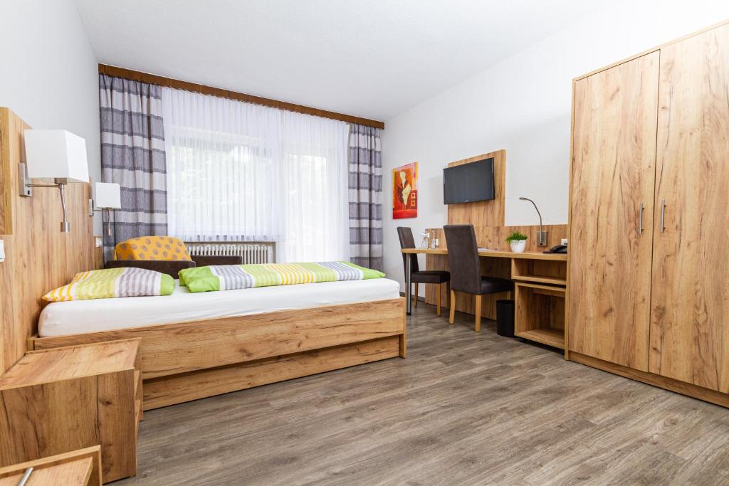 a bedroom with a bed and a desk and a kitchen at Landhotel Georgshof in Hünfeld