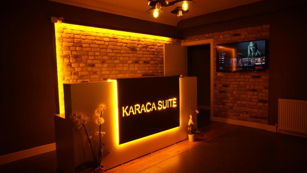 a tv in a living room with a light up sign at Karaca Suite in Tuzla