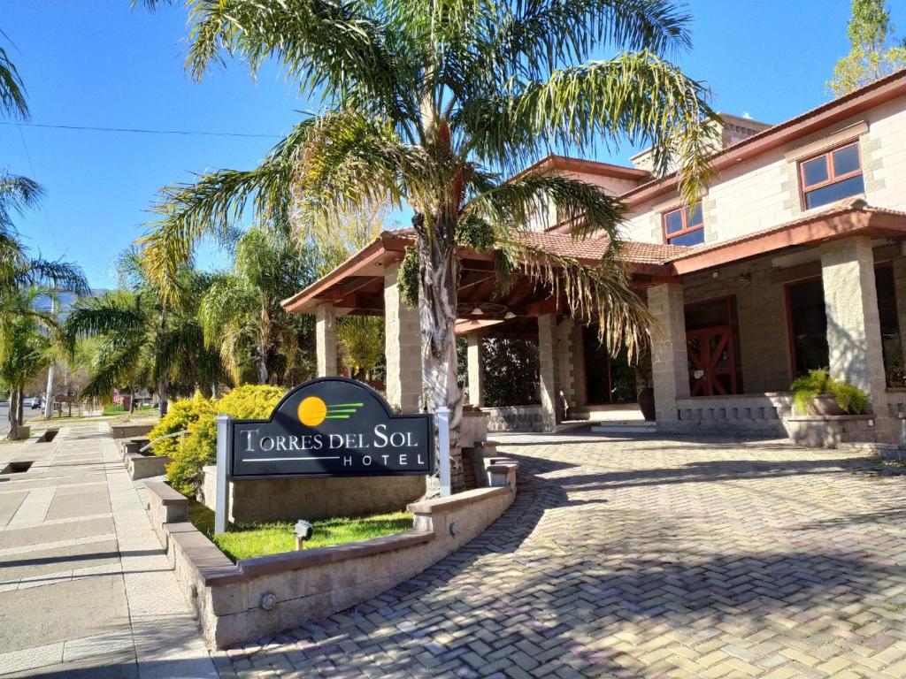 a sign in front of a building with a palm tree at Hotel Torres del Sol in Merlo