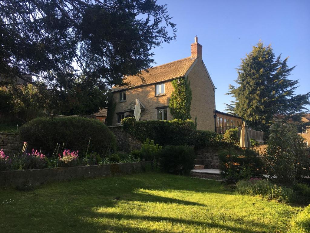 an old house with a garden in the yard at Hollyhock House in Stonesfield