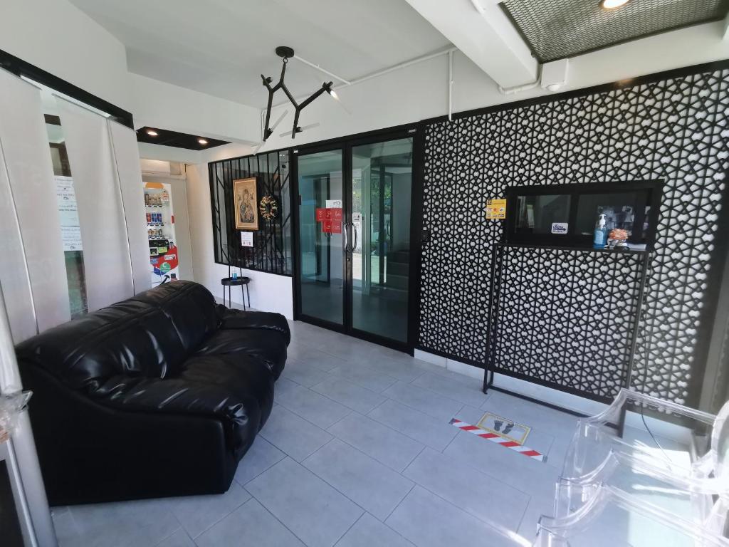 A small sitting area with a black leather sofa, television and glass entrance doors.