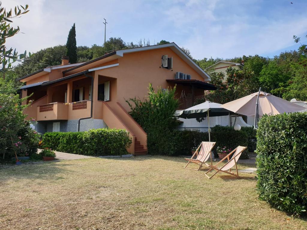 a house with two lawn chairs and an umbrella at Appartamenti Anna in Rio Marina