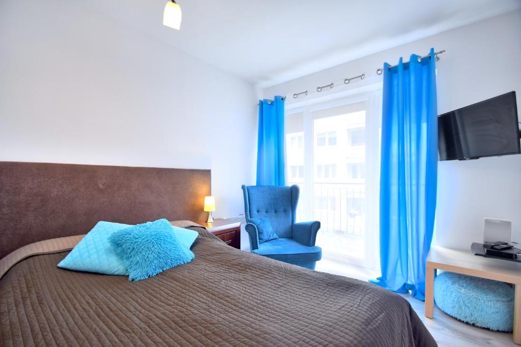 コウォブジェクにあるApartmament Zaplecznaのベッドルーム1室(ベッド1台、青い椅子、窓付)