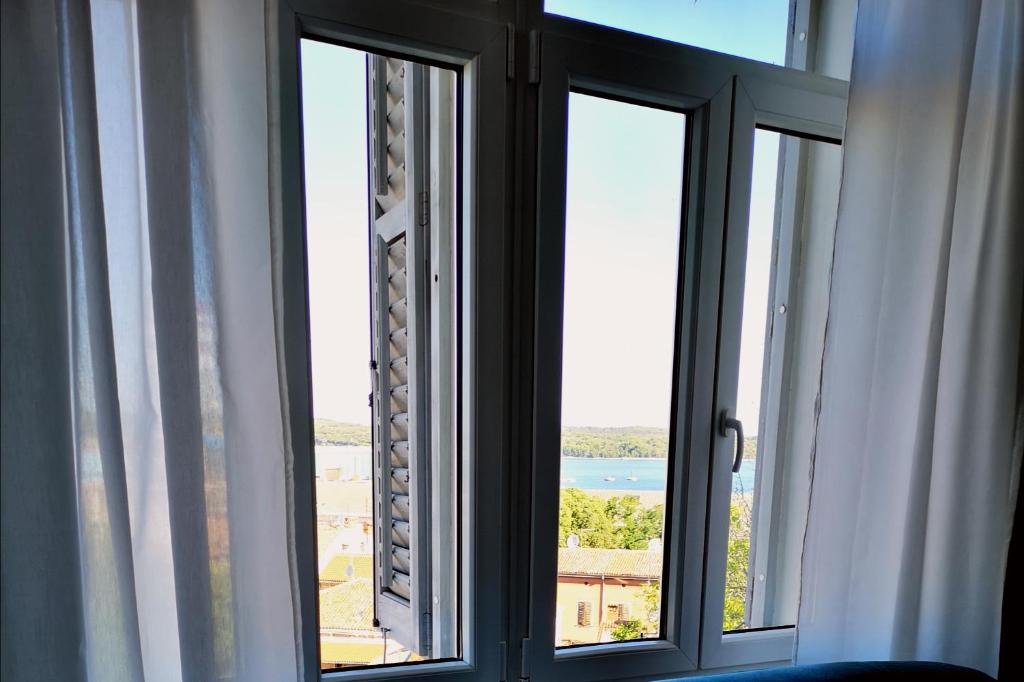 a room with three windows with a view of the water at Old Town in Pula