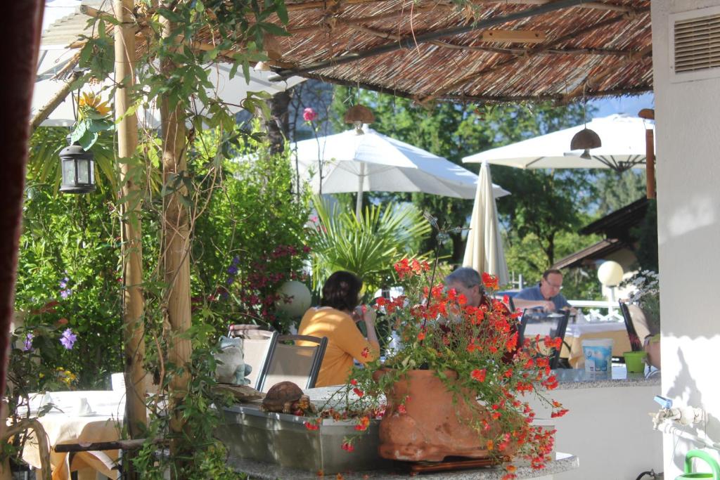 un gruppo di persone sedute a un tavolo sotto un ombrello di Hotel Annabell a Merano