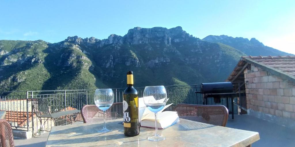 - une bouteille de vin assise sur une table avec deux verres dans l'établissement A CA' DA VILLA, à Castelbianco