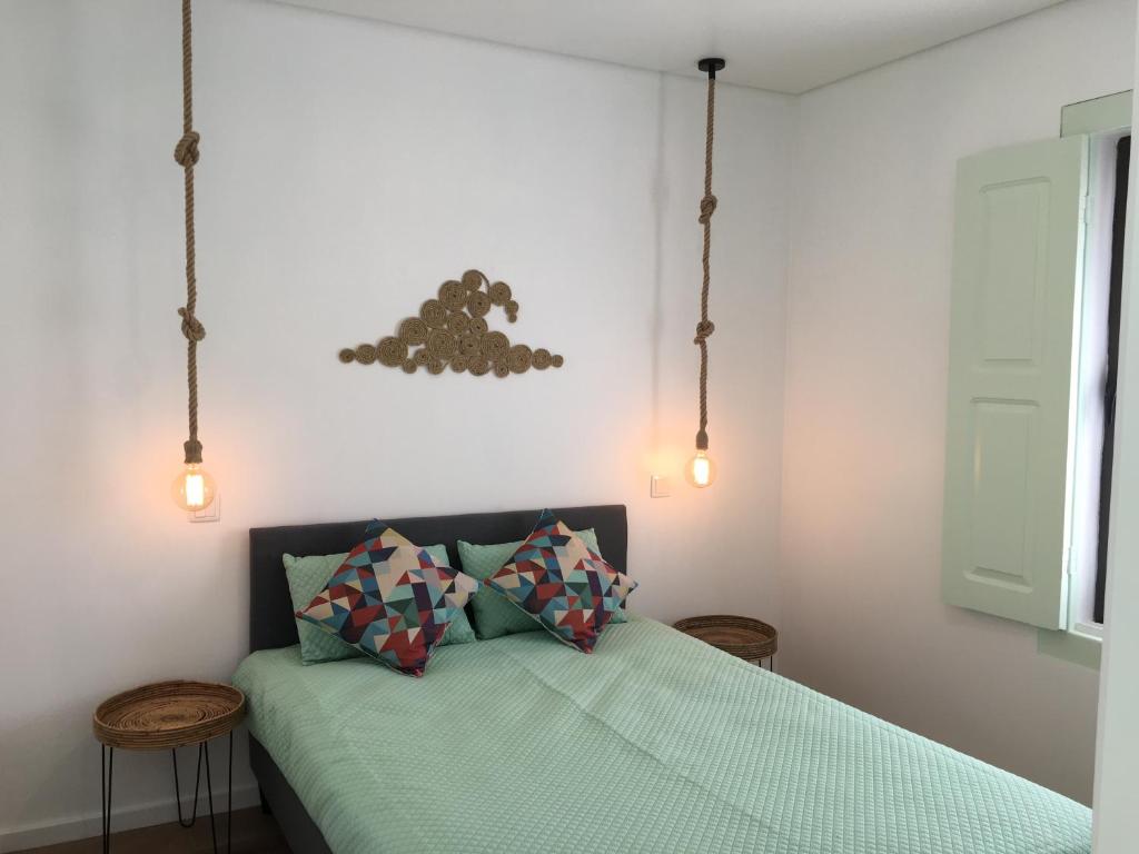 a bedroom with a bed with green sheets and lights at Salty House in Furadouro