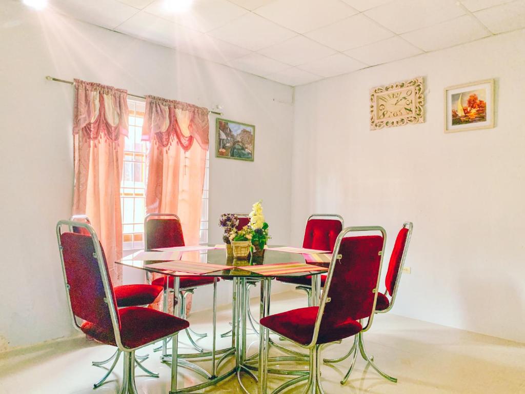 a dining room with a glass table and red chairs at Apartment at Trincity Central Road in Port-of-Spain