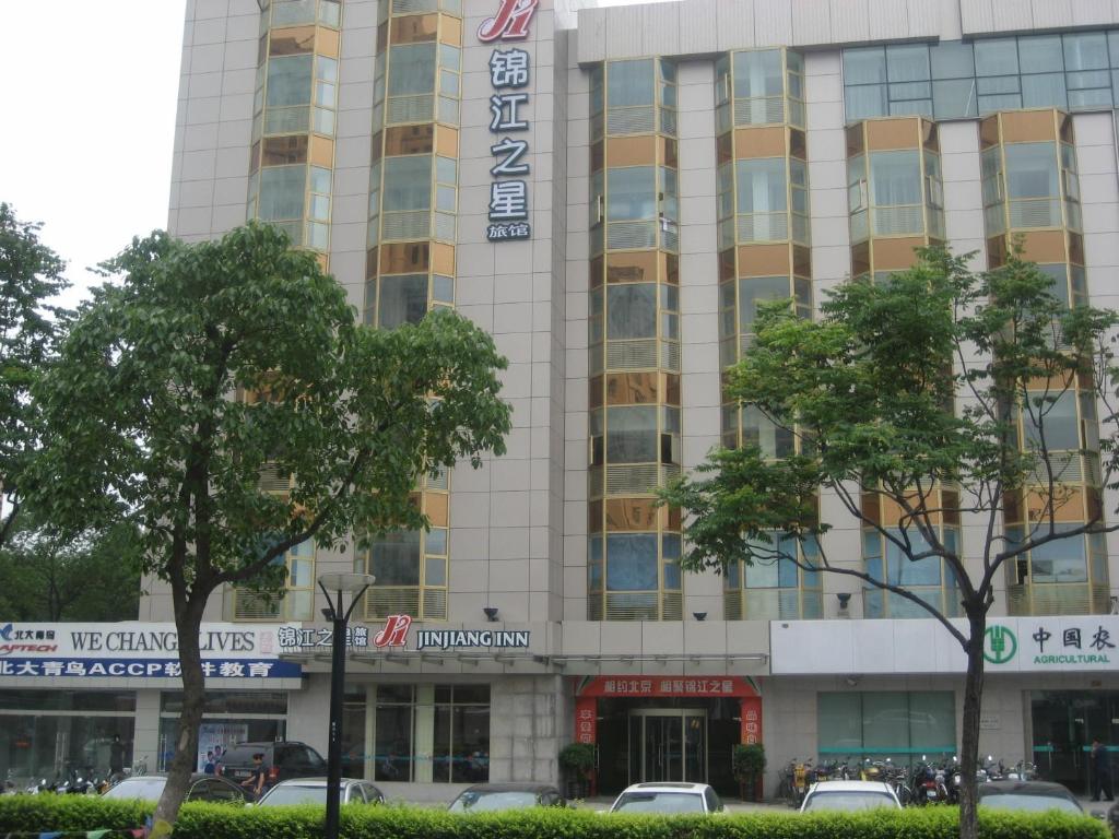 um edifício alto com árvores em frente em Jinjiang Inn - Suzhou Executive Center Hotel em Suzhou