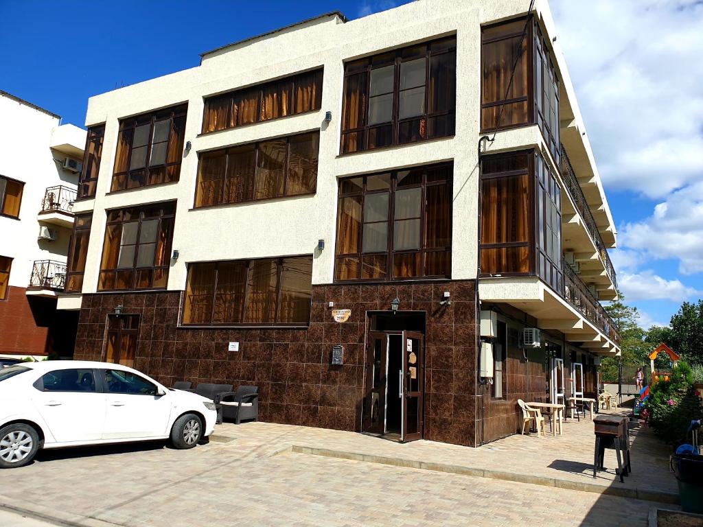 a white car parked in front of a building at Гостевой дом RIVA Джемете in Anapa