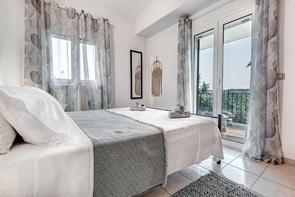 een witte slaapkamer met een bed en een groot raam bij Dream Garden Apartments Corfu in Kommeno