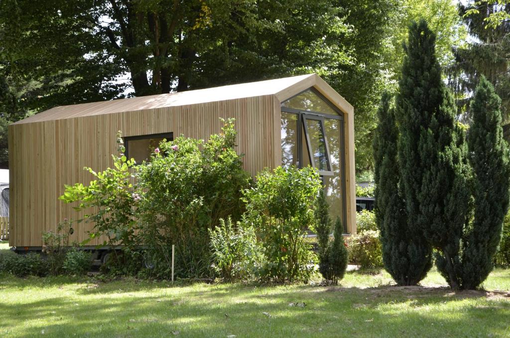 un pequeño cobertizo de madera en un patio con árboles en Das Wiesenhaus: Wohnen im Tiny House direkt am Rhein en Colonia