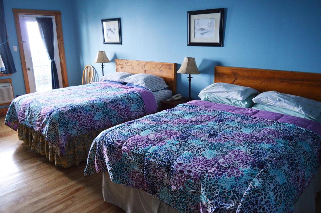 Inn at the Cape : سريرين في غرفة نوم بجدران زرقاء