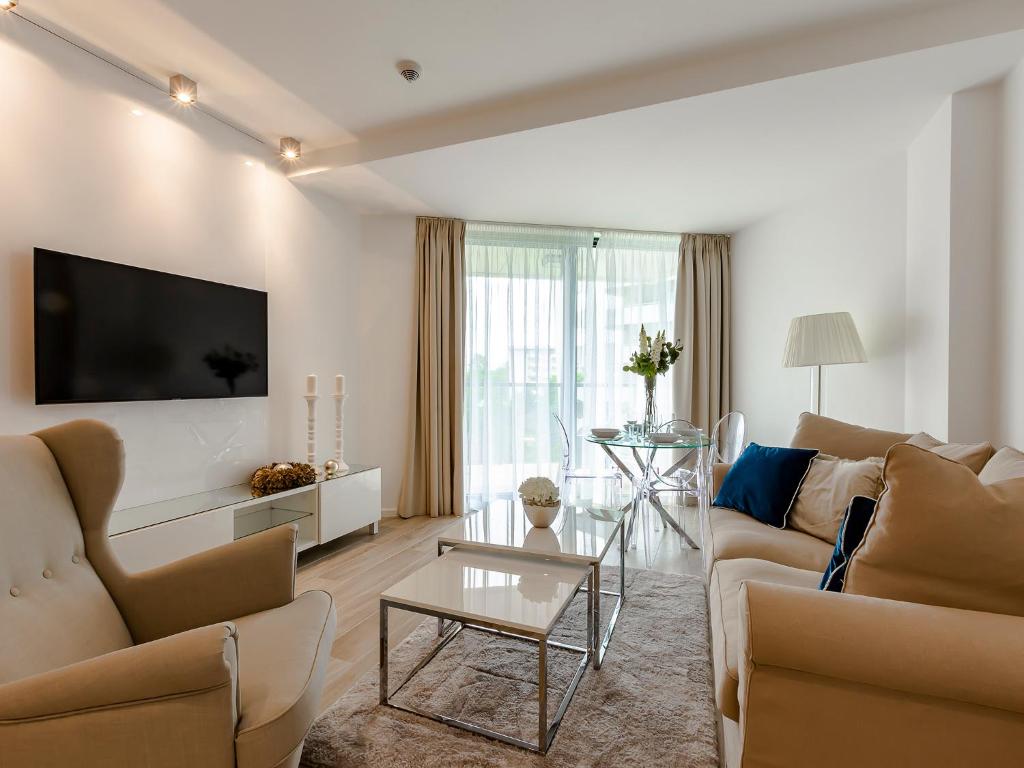 a living room with two couches and a tv at VacationClub – Seaside Park Apartament 316 in Kołobrzeg